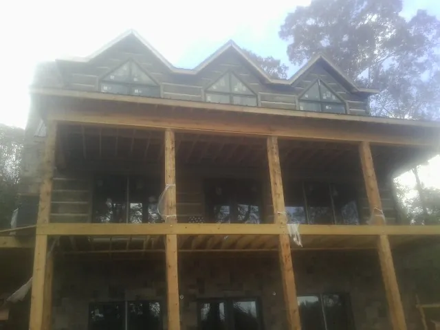 Dormers and porch framing on a large log home under construction — Roof Coating work by our crew in Van Buren