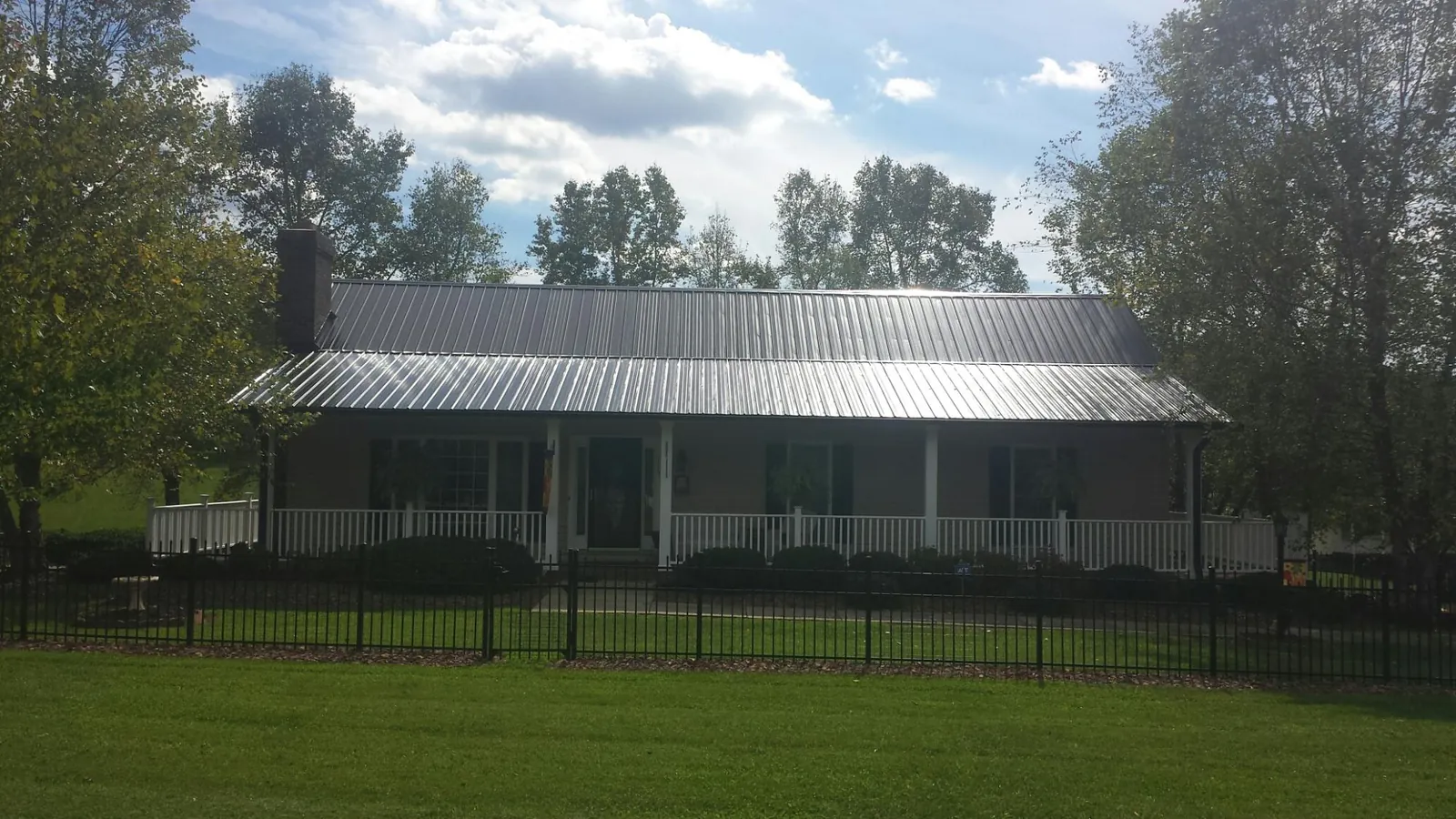 Gray metal roof on a brick ranch with a full width front porch — Gutter Guard Installation work by our crew in Van Buren